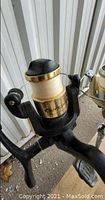 Close-up photo of the outrigger reel labeled Proton attached to a fishing rod, black and gold in color.