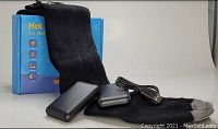 Black heated socks with gray toe area, two black rechargeable battery packs, USB charging cable, and blue retail box in the background.