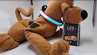 LED light up pet collar shown around a plush Scooby Doo dog with the product box beside it.
