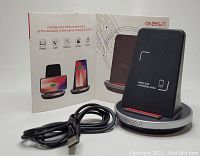 Onecut wireless charging stand on circular base with vertical charging panel, displayed next to black USB charging cable and product box.