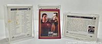 Three Star Trek trading cards shown, two in protective cases and one loose. Cards include text, images of characters from The Next Generation and The Original Series.