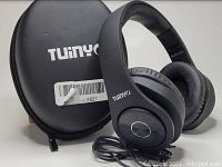 Black Tuinyo wireless rechargeable stereo headphones positioned on top of the matching black carrying case. Wired audio cord coiled near headphones.