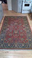 Full view of the Oriental Weavers Egyptian carpet on a wood floor in kitchen setting, showing pattern and edges.