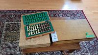 Wood chess board and two wooden storage boxes placed on a table with a rug underneath.