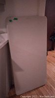 Top view of one grey plastic folding table leaning vertically.