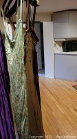 Three dresses hanging on hangers against wall