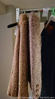 Two wool blazer and skirt sets hanging, showing texture and button details of the fabrics.
