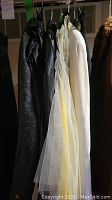 Side view of various skirts and blazers hanging, including light colored tulle skirt and darker velvet or patterned pieces