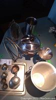 Photo showing stainless chillers, ice bowl, martini glass, and wine holders laid out on table surface.