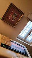 Cityscape photo print and two other artworks laid flat near a window in natural light.