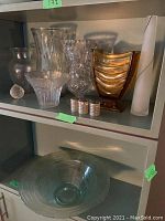 Front view showing the glass bowl and various vases of different shapes, including an amber-colored vase and small candle holders in front.