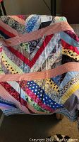 Close-up of vintage handmade quilt showing chevron patchwork and pink and white striped borders