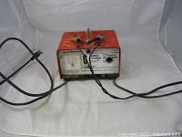 Front view showing battery charger with connected battery clamps and power cord.