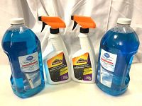 Front view of two large blue Great Value Glass Cleaner Refill bottles and two white Armor All Multi-Purpose Cleaner spray bottles with orange triggers.