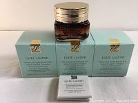 Three sealed teal-green boxes with amber jar on top and sample packet in front