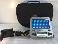 Photo of the goLITE p1 device powered on with blue LED lights lit, next to its power adapter and carrying case.