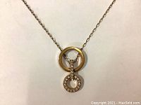 Close-up of the golden ring and round pave setting crystal pendant on the necklace chain.