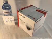Box of Hikvision Turbo HD Dome Camera with size reference bottle and lot number card.