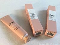 Two peach-colored boxed tubes and one opened tube of VERSED The Shortcut Overnight Facial Peel 15mL shown from above.