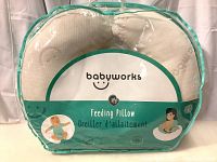 Front view of the Babyworks feeding pillow in its transparent packaging showing the brand name and product type.