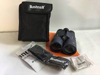 Binoculars with carrying case, strap, instruction manual and cleaning cloth displayed on white surface.
