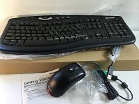 Keyboard and mouse laid on top of box with instruction pamphlet visible, keyboard not wrapped but mouse in plastic bag with attached cable and USB connection.