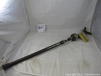 Side view of the PRIMOS TRIGGER Stick monopod lying on a white cloth, showing its length and camouflage pattern.