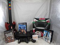 Photo showing the PlayStation 2 console, controller, American Idol, Guitar Hero 2, and Dance Dance Revolution game cases, DDR dance pad, and Guitar Hero guitar controller.