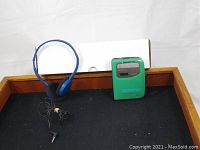 Green Sony Walkman portable cassette player with blue wired headphones, displayed on black surface.