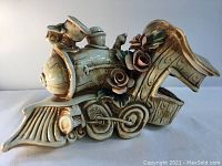 Side view of the vintage ceramic train locomotive showing detailed floral accents and glaze finish.
