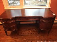 Front view of desk under window showing curved top and drawer layout