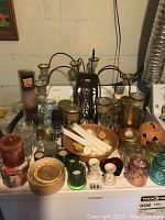 Full view of the assortment of candle holders, candles, and decorative holders on a freezer surface.