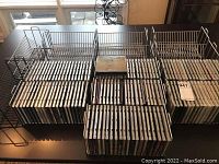 Overview of CDs arranged in multiple holders alongside empty metal wire and plastic racks on a tabletop