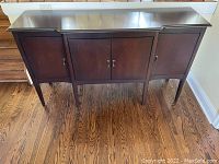 Front view of dark wood buffet sideboard showing three-door design