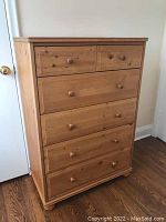 Front perspective view of chest showing five drawers with wooden knobs and natural pine wood finish.