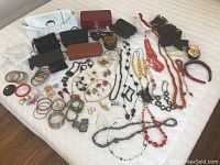 Full overview of all items showing purses, wallets, jewelry including bracelets, necklaces, earrings, and hair accessories spread on bed
