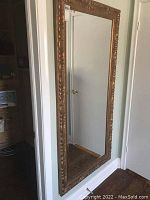 Full-length mirror leaning against wall showing overall appearance