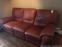 Front view of brown Italian leather three-seat sofa against wall