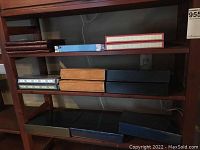 Photo showing multiple photo albums arranged on three shelves, including floral, tan, black, blue, and green albums.