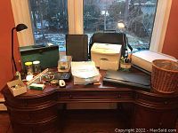 Photo showing the full collection on a desk near window: printers, shredder, lamps, portfolios, baskets, and office supplies.