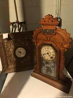 View showing two old carved wooden mantel clocks side by side