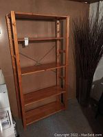Full view of wooden shelving unit with five shelves and vertical supports with adjustment holes.