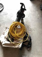 Full view of Toro Super Blower with yellow extension cord and white collection bag attached.