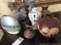 Front view of vases and metal ballerina figurine arranged on dark surface