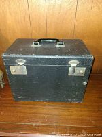 Closed black hard carrying case with metal latches and plastic handle