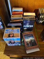 Lot showing various DVD and VHS collections including The Hobbit, Sopranos, Power, and Little House on the Prairie.