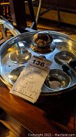 Stainless steel egg poaching pan with five egg molds and glass lid, shown with auction tag
