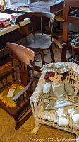 Wooden highchair, wooden child size rocker with damage, and wicker rocker holding a fabric doll in a pet-friendly home environment.