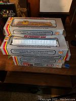 Stack of boxed A.H.M. HO scale train cars showing packaging with branding and label details.