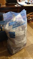 Large clear plastic Ziploc bag containing white cooling and heating mattress pad designed for king size bed